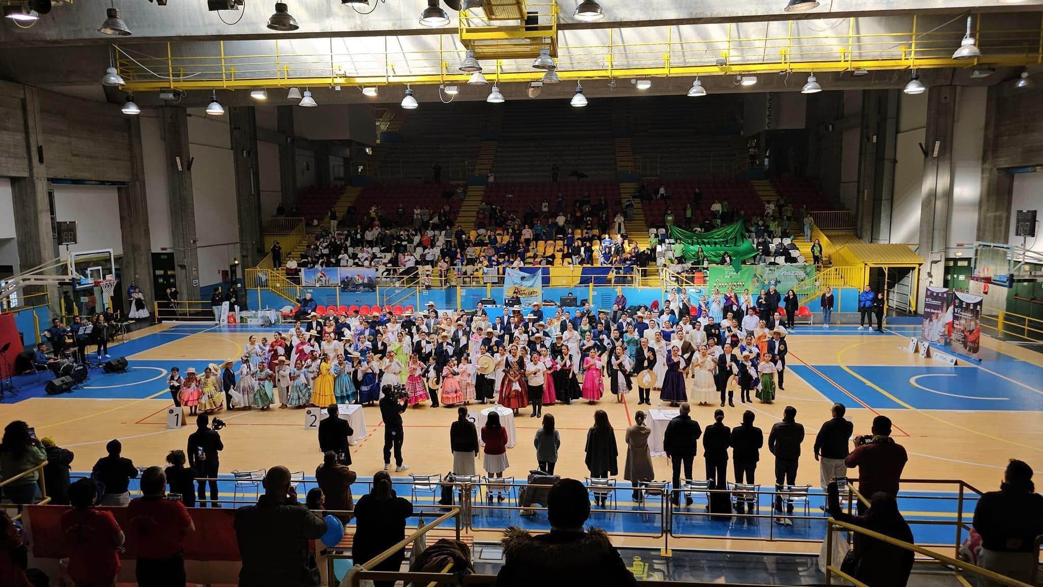 Vista general del pabellón PalaRavizza de Pavía con las parejas participantes formadas en la pista durante el Concurso Europeo de Marinera 2023
